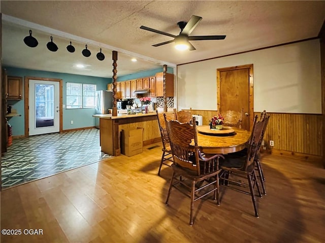210 S 3 Rd, St, Arma, KS 66712 - dining room featuring ceiling fan, a textured ceiling, wainscoting, wood finished floors, and wooden walls