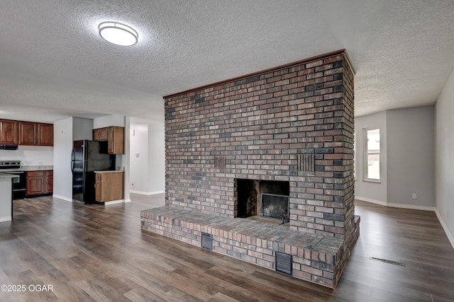 720 Sheridan Ave, Carl Junction, MO 64834 - unfurnished living room featuring a textured ceiling, dark wood finished floors, baseboards, and a brick fireplace