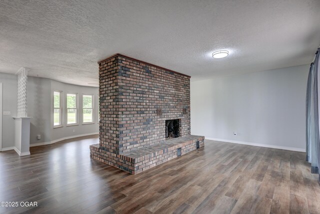 720 Sheridan Ave, Carl Junction, MO 64834 - unfurnished living room featuring a textured ceiling, wood finished floors, a brick fireplace, and baseboards