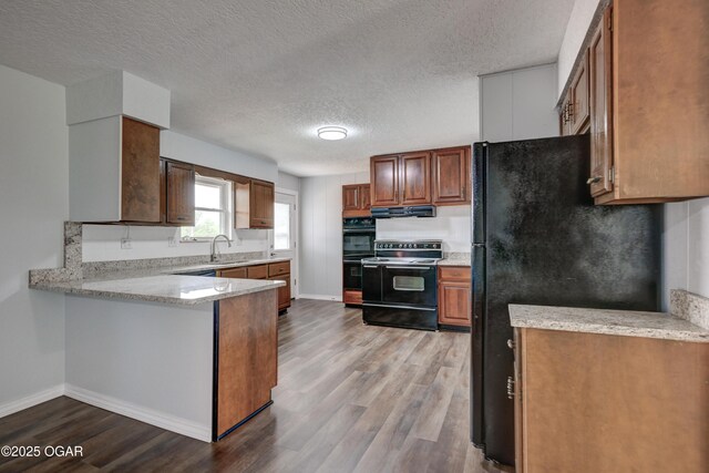 720 Sheridan Ave, Carl Junction, MO 64834 - kitchen with black appliances, a peninsula, a textured ceiling, under cabinet range hood, and wood finished floors