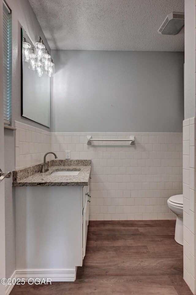 720 Sheridan Ave, Carl Junction, MO 64834 - bathroom with tile walls, a textured ceiling, vanity, wood finished floors, and toilet