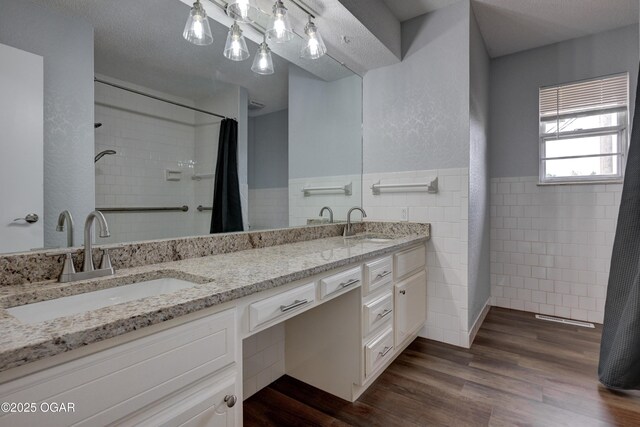 720 Sheridan Ave, Carl Junction, MO 64834 - bathroom featuring tile walls, double vanity, wood finished floors, a shower with curtain, and a wainscoted wall