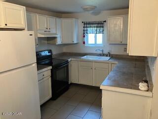 620 W 5th St, Baxter Springs, KS 66713 - kitchen featuring freestanding refrigerator, black range with electric stovetop, extractor fan, a sink, and light tile patterned flooring