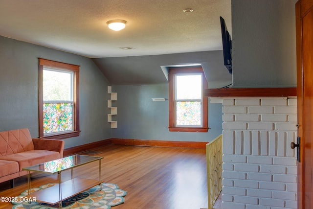 702 W Daugherty St, Webb City, MO 64870 - living room featuring wood finished floors, healthy amount of natural light, vaulted ceiling, baseboards, and a textured ceiling