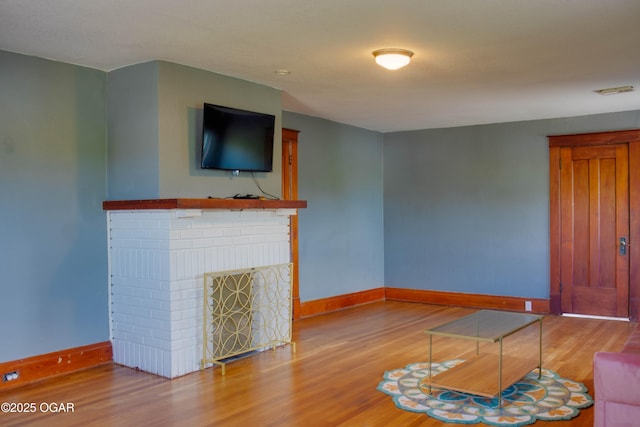 702 W Daugherty St, Webb City, MO 64870 - unfurnished living room featuring baseboards, a brick fireplace, and wood finished floors