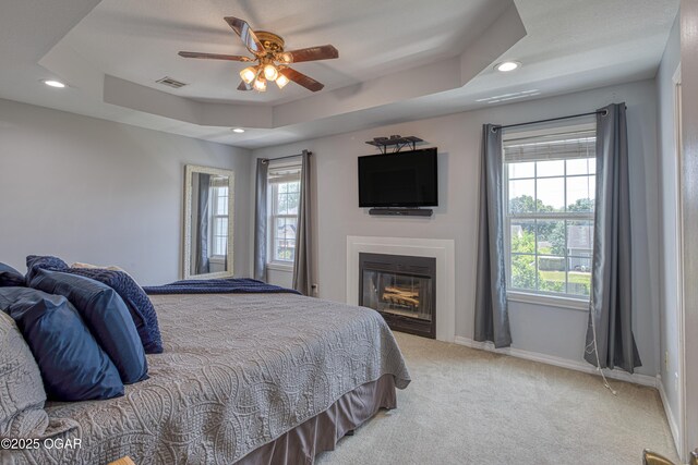 408 W Walton Ave, Carl Junction, MO 64834 - bedroom with light carpet, baseboards, a raised ceiling, a glass covered fireplace, and recessed lighting
