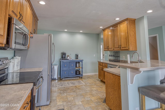 408 W Walton Ave, Carl Junction, MO 64834 - kitchen with stainless steel appliances, stone finish flooring, brown cabinetry, a breakfast bar area, and recessed lighting