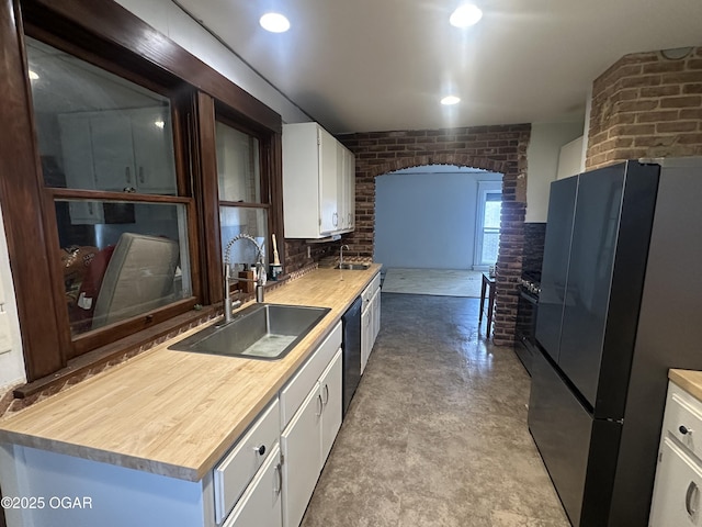 206 S Connor Ave, Joplin, MO 64801 - kitchen featuring freestanding refrigerator, a sink, brick wall, white cabinets, and a fireplace