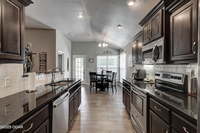 1692 Betenbough Way, Webb City, MO 64870 - kitchen featuring appliances with stainless steel finishes, lofted ceiling, a chandelier, a sink, and dark stone counters