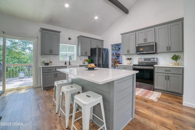 2010 Cherry St, Seneca, MO 64865 - kitchen featuring appliances with stainless steel finishes, gray cabinetry, beam ceiling, light countertops, and a kitchen breakfast bar