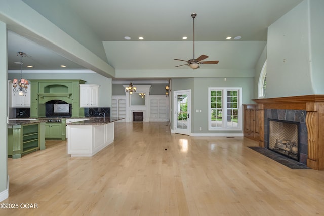 1704 Liam St, Carthage, MO 64836 - unfurnished living room with a tiled fireplace, ceiling fan, a chandelier, light wood-style floors, and recessed lighting