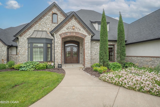 1704 Liam St, Carthage, MO 64836 - entrance to property with stone siding, french doors, a shingled roof, and a yard