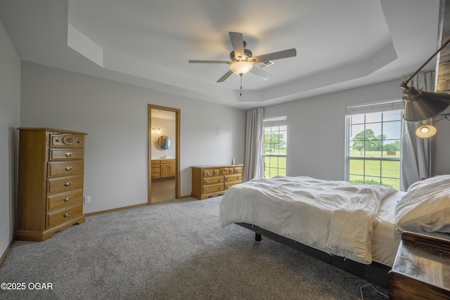 201 Canary Ln, Commerce, OK 74339 - carpeted bedroom with a tray ceiling, baseboards, ensuite bath, and ceiling fan