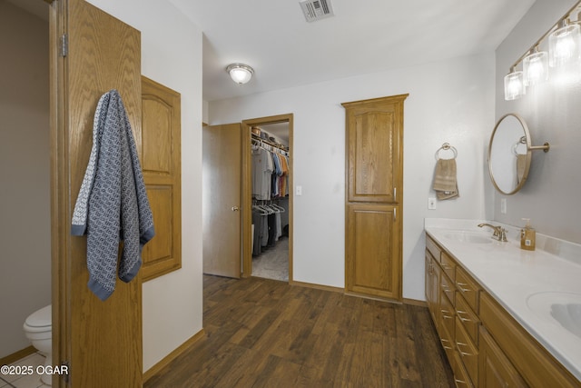 201 Canary Ln, Commerce, OK 74339 - bathroom with wood finished floors, double vanity, toilet, a spacious closet, and baseboards