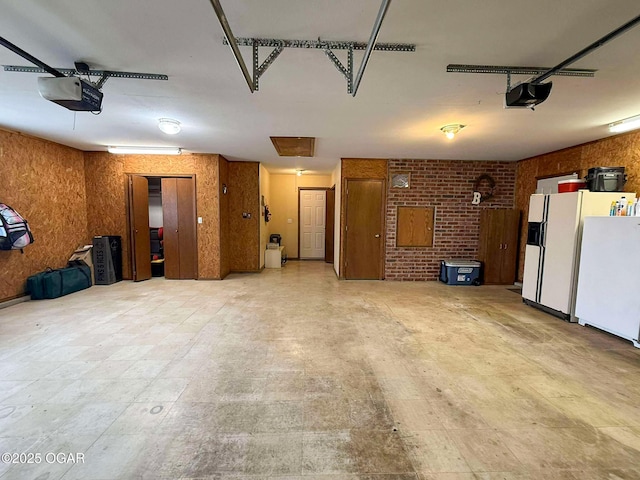 201 Canary Ln, Commerce, OK 74339 - garage featuring a garage door opener, white fridge with ice dispenser, and freestanding refrigerator