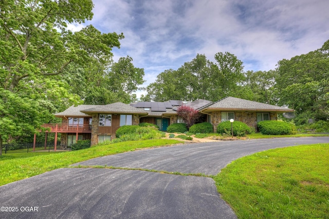 13495 Dogwood Rd, Carthage, MO 64836 - view of front of home with stone siding, driveway, roof mounted solar panels, and a deck