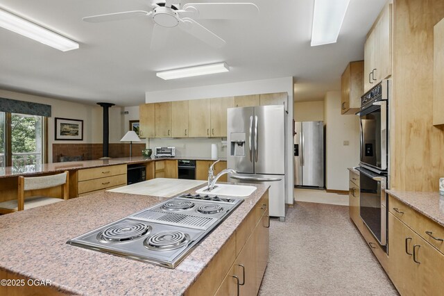 13495 Dogwood Rd, Carthage, MO 64836 - kitchen featuring stainless steel appliances, a wood stove, a sink, light brown cabinets, and ceiling fan