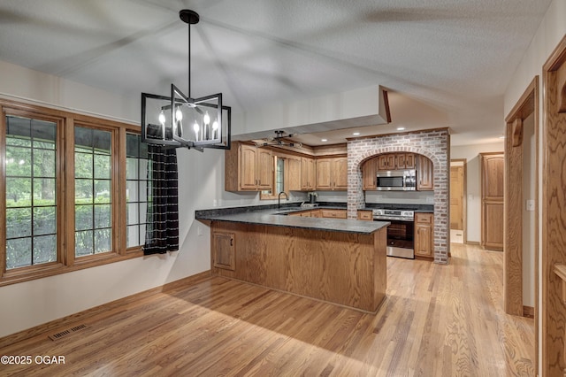 1330 Stoneledge Ln, Neosho, MO 64850 - kitchen with appliances with stainless steel finishes, dark countertops, light wood-style floors, a peninsula, and a sink