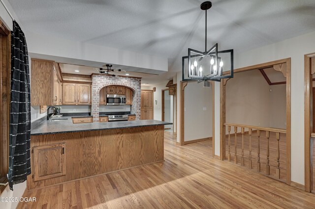 1330 Stoneledge Ln, Neosho, MO 64850 - kitchen with stainless steel appliances, light wood-type flooring, dark countertops, a sink, and a peninsula