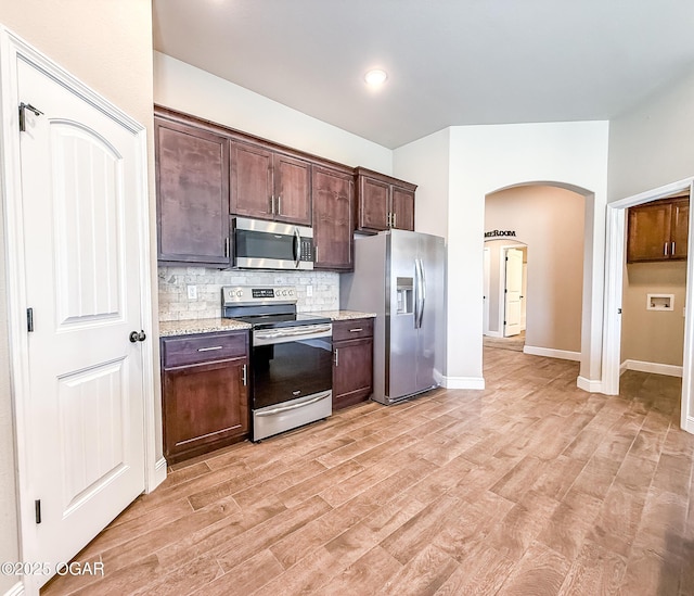 815 Delaney Dr, Carl Junction, MO 64834 - kitchen with appliances with stainless steel finishes, arched walkways, backsplash, light wood-type flooring, and dark brown cabinets