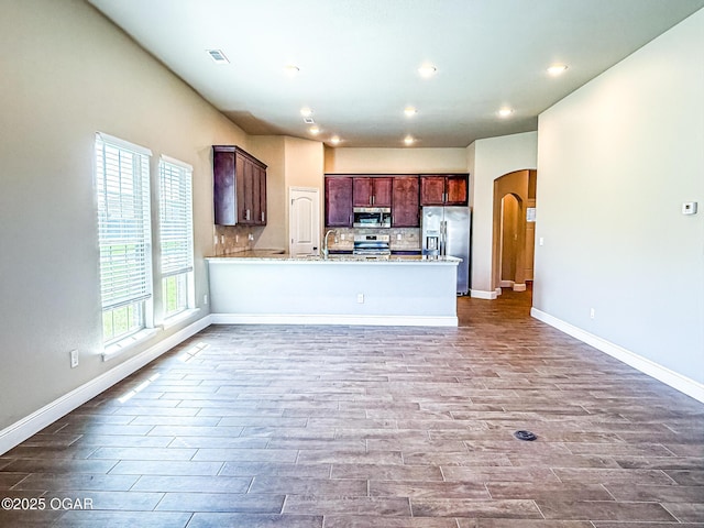 815 Delaney Dr, Carl Junction, MO 64834 - kitchen featuring appliances with stainless steel finishes, arched walkways, light countertops, wood finished floors, and a peninsula
