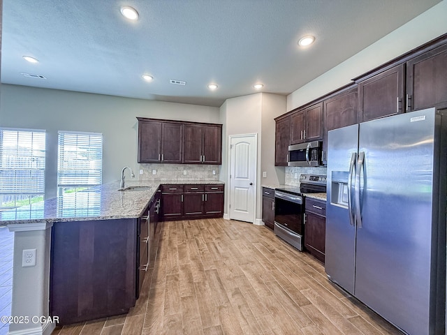 815 Delaney Dr, Carl Junction, MO 64834 - kitchen with stainless steel appliances, a peninsula, light wood finished floors, tasteful backsplash, and dark brown cabinets