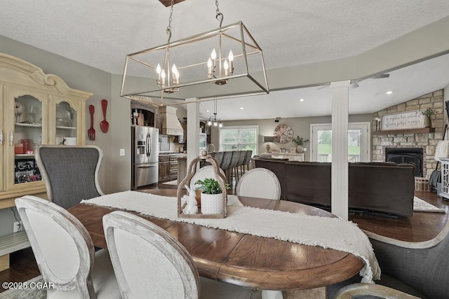 7870 County Lane 287, Carl Junction, MO 64834 - dining space featuring ornate columns, a fireplace, wood finished floors, a chandelier, and a textured ceiling
