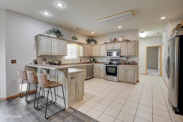 4320 Wisteria Way, Joplin, MO 64801 - kitchen featuring appliances with stainless steel finishes, a sink, a peninsula, a kitchen breakfast bar, and baseboards