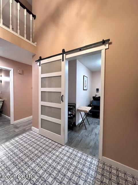 3331 Willow Ln, Joplin, MO 64801 - hallway featuring a barn door, baseboards, a high ceiling, and wood finished floors