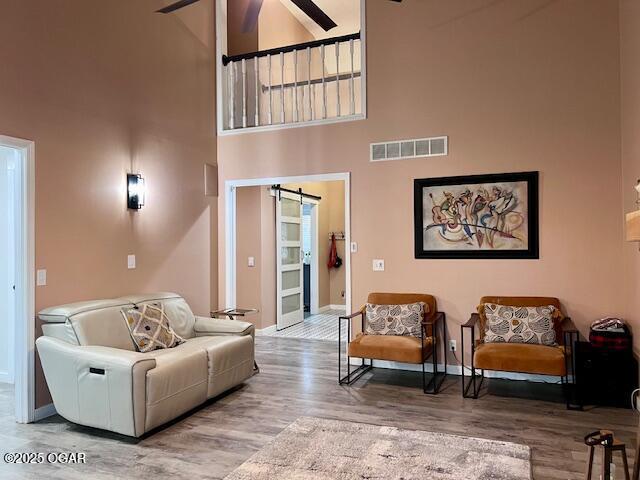 3331 Willow Ln, Joplin, MO 64801 - living room with high vaulted ceiling, a ceiling fan, baseboards, wood finished floors, and a barn door