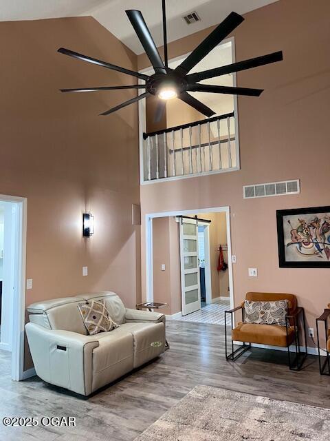 3331 Willow Ln, Joplin, MO 64801 - living room with high vaulted ceiling, a ceiling fan, wood finished floors, baseboards, and a barn door