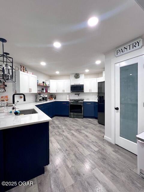 3331 Willow Ln, Joplin, MO 64801 - kitchen featuring stainless steel range, black fridge with ice dispenser, blue cabinets, a sink, and light countertops