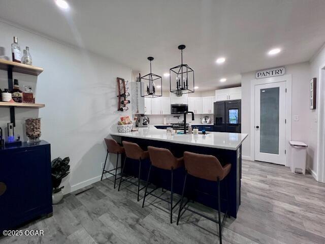 3331 Willow Ln, Joplin, MO 64801 - kitchen with a peninsula, a breakfast bar area, baseboards, light wood finished floors, and white cabinets