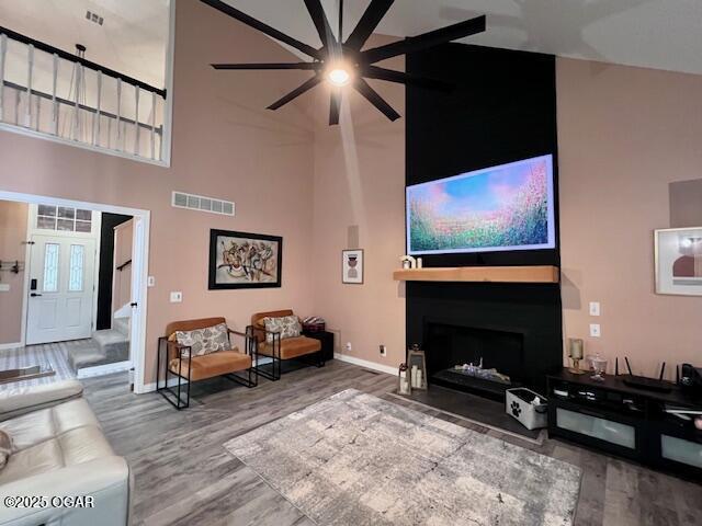 3331 Willow Ln, Joplin, MO 64801 - living room featuring a towering ceiling, wood finished floors, baseboards, ceiling fan, and a fireplace with flush hearth