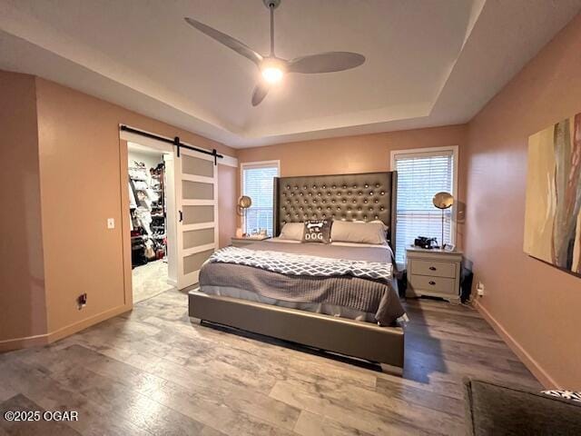 3331 Willow Ln, Joplin, MO 64801 - bedroom with a raised ceiling, baseboards, a barn door, wood finished floors, and a walk in closet