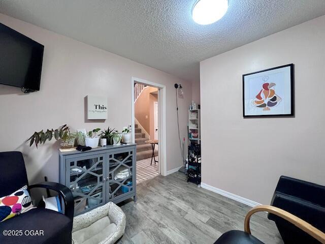 3331 Willow Ln, Joplin, MO 64801 - living area featuring wood finished floors, a textured ceiling, stairs, and baseboards