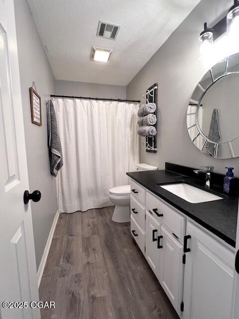 3331 Willow Ln, Joplin, MO 64801 - bathroom featuring a textured ceiling, vanity, toilet, wood finished floors, and a shower with shower curtain