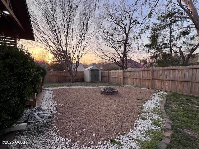 3331 Willow Ln, Joplin, MO 64801 - yard at dusk featuring a fenced backyard and a fire pit