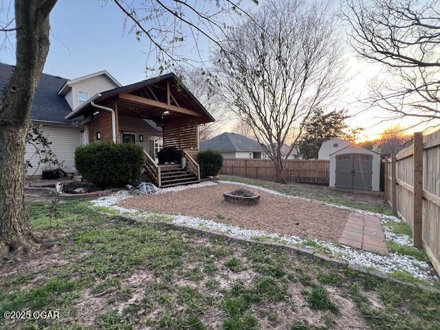 3331 Willow Ln, Joplin, MO 64801 - yard at dusk with a fire pit, a fenced backyard, and a porch