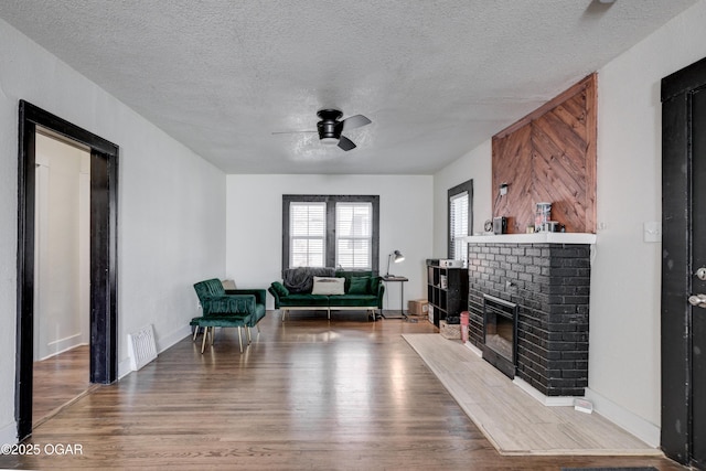 118 N Byers Ave, Joplin, MO 64801 - living area with a ceiling fan, wood finished floors, a textured ceiling, and a brick fireplace