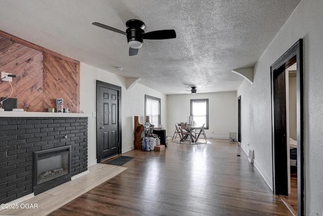 118 N Byers Ave, Joplin, MO 64801 - living room with ceiling fan, a textured ceiling, a brick fireplace, wood finished floors, and wooden walls