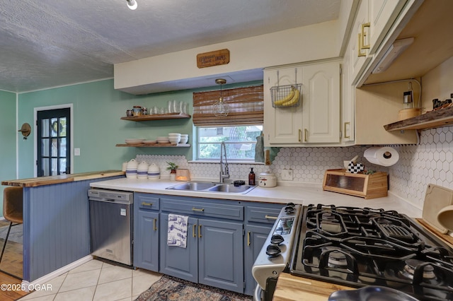509 Brentwood Dr, Carl Junction, MO 64834 - kitchen featuring stainless steel dishwasher, open shelves, blue cabinetry, gas range, and a textured ceiling