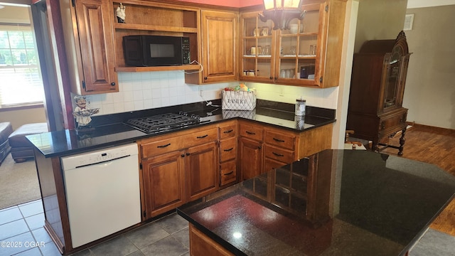 3002 S Main St, Galena, KS 66739 - kitchen featuring black appliances, brown cabinetry, dark countertops, backsplash, and glass insert cabinets