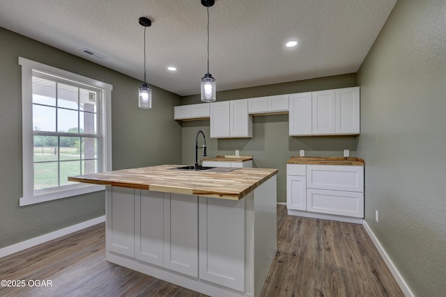 26204 King Ln, Carl Junction, MO 64834 - kitchen featuring wood counters, white cabinetry, dark wood-type flooring, a center island with sink, and a textured ceiling