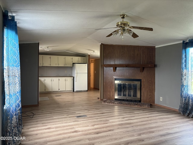 1346 SE Gum Ln, Baxter Springs, KS 66713 - unfurnished living room with lofted ceiling, light wood-type flooring, a ceiling fan, and a glass covered fireplace