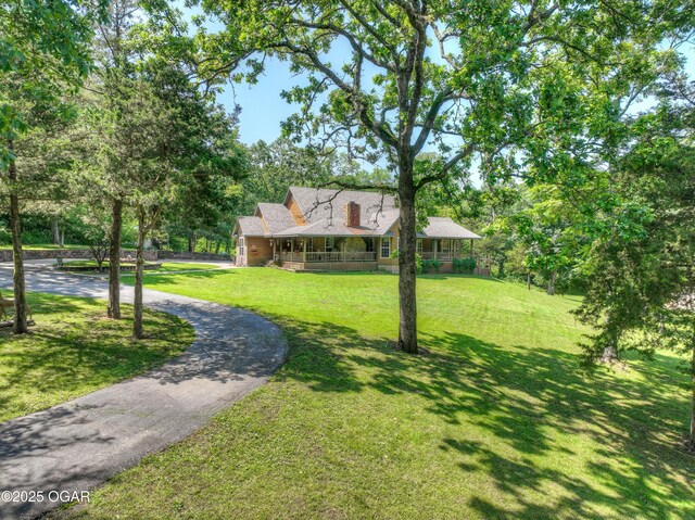 9404 County Lane 121, Carthage, MO 64836 - view of front facade featuring curved driveway, a front lawn, a porch, and view of scattered trees