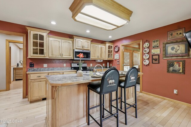 9404 County Lane 121, Carthage, MO 64836 - kitchen featuring appliances with stainless steel finishes, light wood-style floors, light countertops, a breakfast bar, and glass insert cabinets