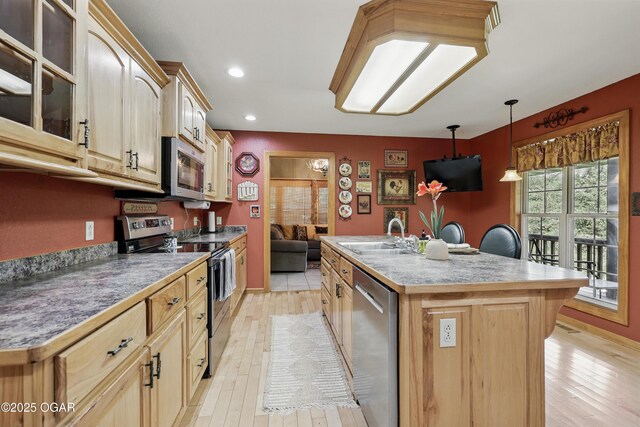 9404 County Lane 121, Carthage, MO 64836 - kitchen with stainless steel appliances, a kitchen island with sink, light wood finished floors, glass insert cabinets, and decorative light fixtures