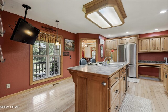 9404 County Lane 121, Carthage, MO 64836 - kitchen with freestanding refrigerator, light wood finished floors, a center island with sink, dishwashing machine, and pendant lighting