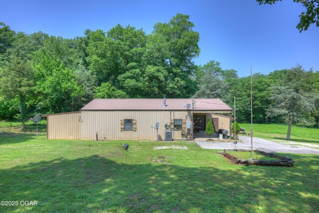 9404 County Lane 121, Carthage, MO 64836 - back of property with a lawn, a metal roof, an outbuilding, and a wooded view